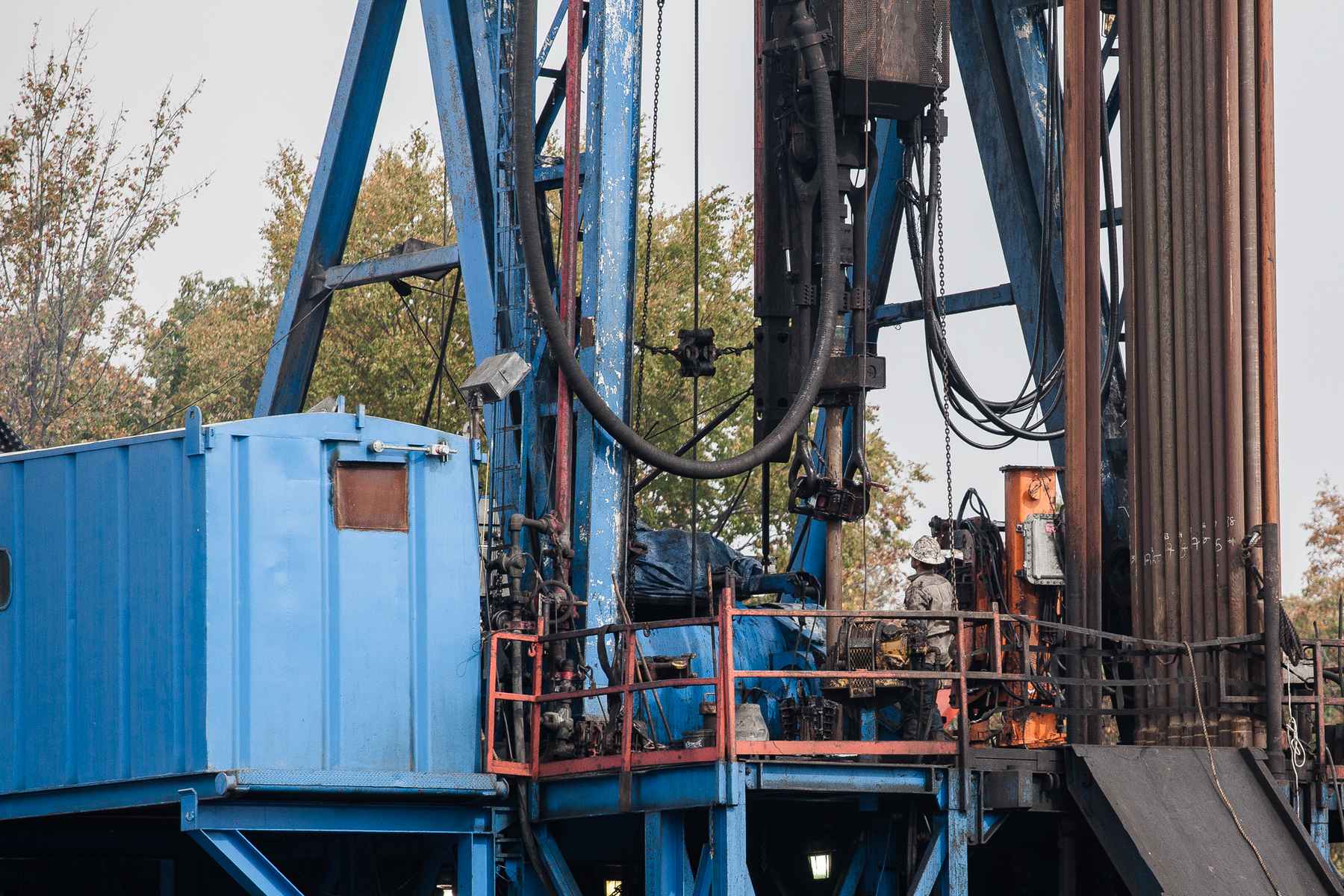 A worker looks on as a freshly loaded section of pipe is guided into the drill rig. To the right hang additional pipe sections, which will be loaded into place in successive fashion (photo: Chad Shmukler). fracking drilling rig
