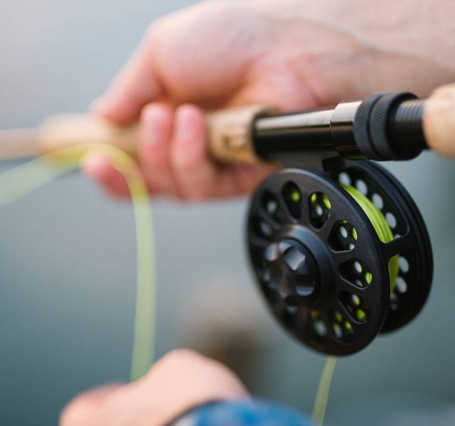 fly fisherman holding fly rod and reel