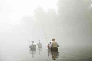 crowd of anglers fly fishing stream