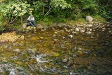 man fly fishing small creek