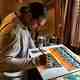 Artist Dereck DeYoung at work hand-painting fabric panels slated for use in a Vedavoo Spinner Daypack. Dereck DeYoung at work Vedavoo bag